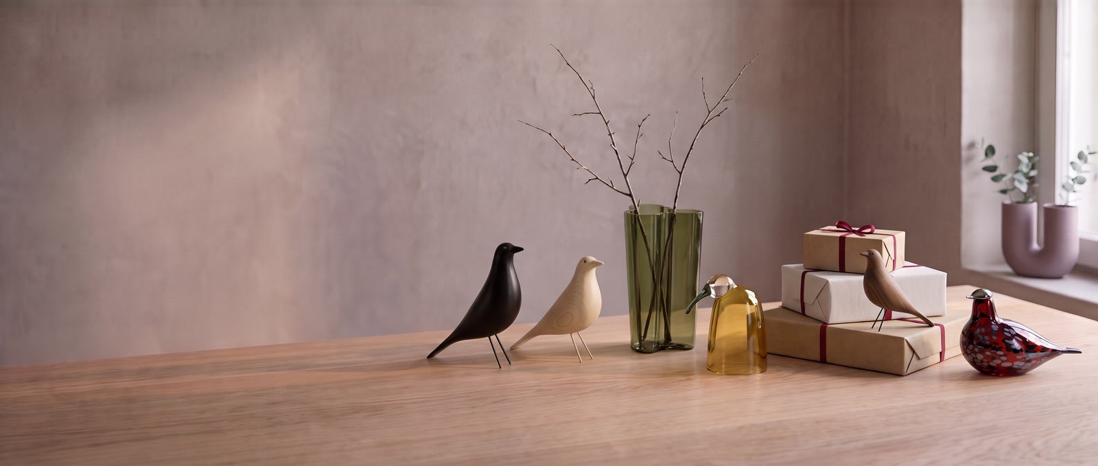 Vitra Eames House Birds, L'Oiseau, an Iittala Aalto Finlandia vase, Iittala Birds by Toikka, wrapped gifts and a Muuto Kink vase on an oak table